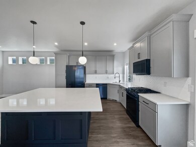 Kitchen with black appliances, light countertops, a sink, and a kitchen island