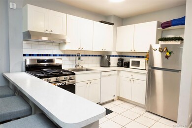 Kitchen with appliances with stainless steel finishes, decorative backsplash, a kitchen breakfast bar, and white cabinets