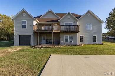 Rear view of property with a lawn, a deck, and an attached garage