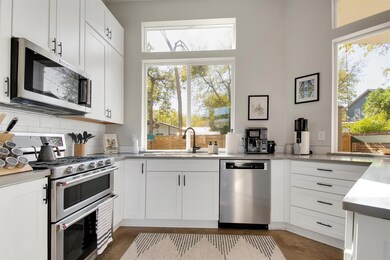 Designed for both style and function, this bright kitchen features KitchenAid appliances, quartz countertops, and custom shaker cabinets. Large windows fill the space with natural light and offer a peaceful view of the private backyard.