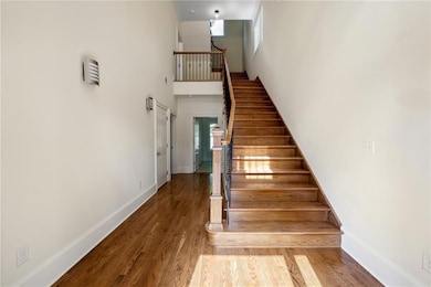 Staircase with hardwood / wood-style floors and a high ceiling