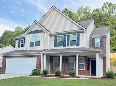 View of front of house featuring brick siding, driveway, covered porch, and a garage