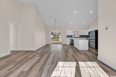 Kitchen with high vaulted ceiling, open floor plan, a chandelier, pendant lighting, and backsplash