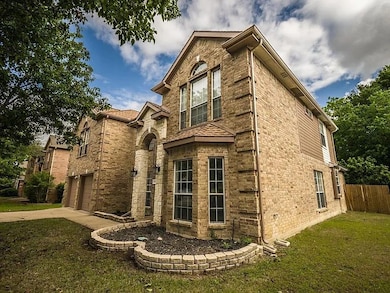 Traditional-style home featuring driveway, brick siding, and an attached garage