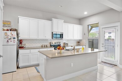 Kitchen featuring white cabinets, tasteful backsp