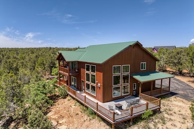 Back of property with a metal roof, a wooded view, a wooden deck, and a balcony