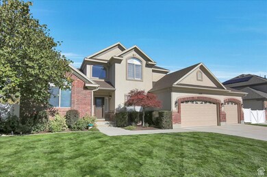 Traditional-style house with stucco siding, brick siding, driveway, and an attached garage