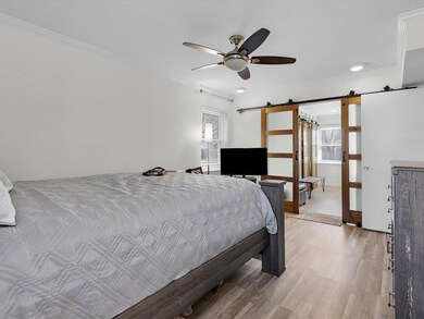 Bedroom featuring ornamental molding, a barn door,