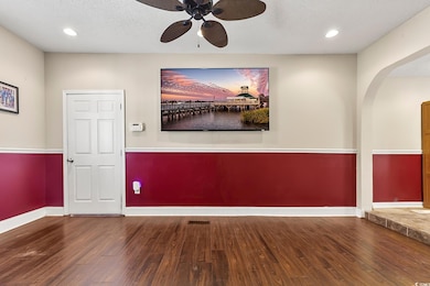 Empty room featuring recessed lighting, a ceiling fan, dark wood-type flooring, arched walkways, and a textured ceiling