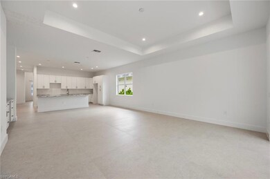 Unfurnished living room with a tray ceiling, recessed lighting, and light floors