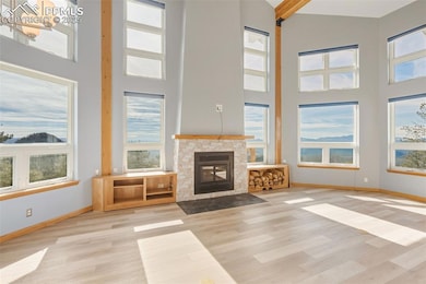 Unfurnished living room featuring a fireplace with flush hearth, wood finished floors, and a high ceiling