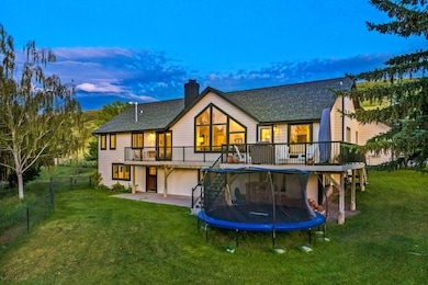 Back of property with a trampoline, roof with shingles, a patio area, a chimney, and a wooden deck