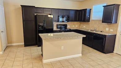 Kitchen with black appliances, light tile pattern