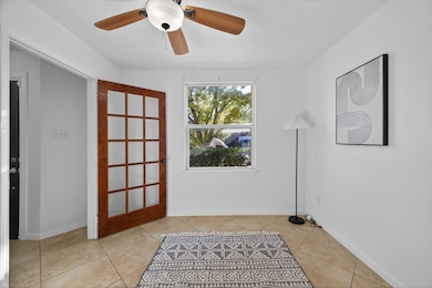 Doorway featuring a ceiling fan and tile patterned flooring