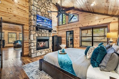 Bedroom with wood ceiling, wooden walls, dark wood finished floors, and a stone fireplace