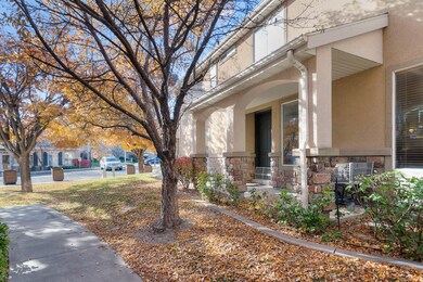 View of home's exterior with stucco siding, stone siding, covered porch, and mature landscape