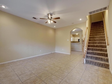 Spare room featuring recessed lighting, light tile patterned floors, arched walkways, stairs, and a ceiling fan