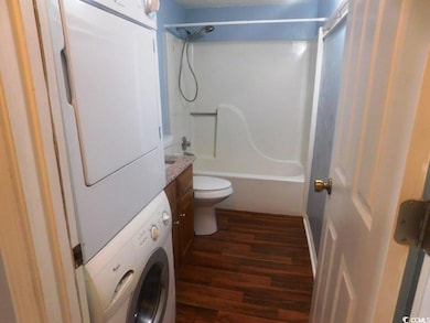 Full bath featuring stacked washer / dryer, wood finished floors, tub / shower combination, and vanity
