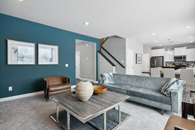 The spacious family gathering area seamlessly connects to the kitchen area, perfect for entertaining. It also features many large windows providing warm natural light. (Photo of decorated model, actual home's finishes may vary slightly)