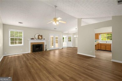 Unfurnished living room featuring dark wood-style flooring, a textured ceiling, a ceiling fan, a tile fireplace, and french doors