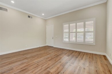Spare room with ornamental molding, visible vents, light wood finished floors, and baseboards
