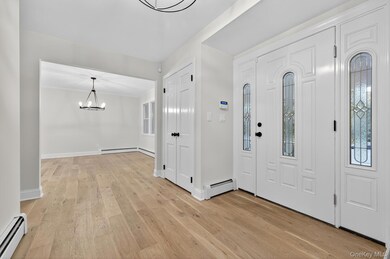 Entryway with baseboard heating, light wood-style flooring, and a chandelier
