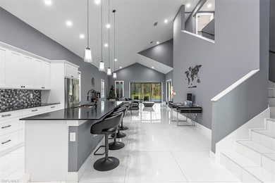 Kitchen with open floor plan, a center island with sink, white cabinetry, pendant lighting, and a kitchen breakfast bar