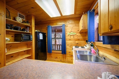 Kitchen with black appliances, wooden walls, and s