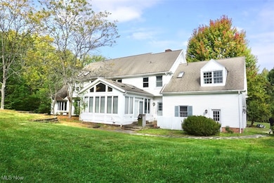 Rear view of property with a sunroom, a yard, and roof with shingles