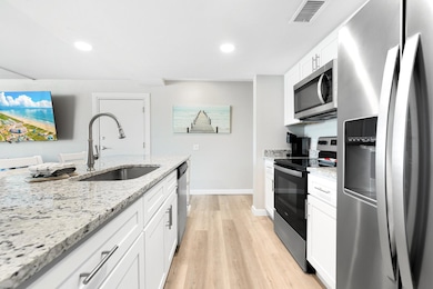 Kitchen featuring white cabinets, a sink, light w