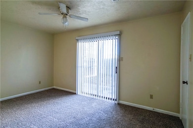 Carpeted empty room with baseboards, ceiling fan,