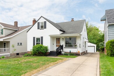 View of front facade featuring a front lawn, covered porch, an outdoor structure, and a garage