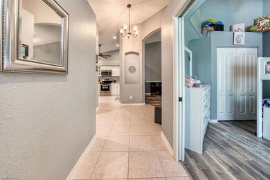 Hallway featuring arched walkways, light tile patterned flooring, a chandelier, and a textured wall
