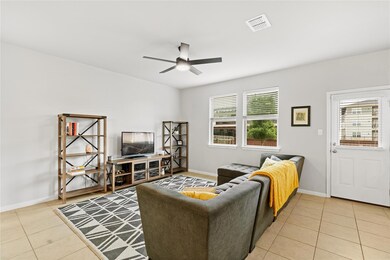 Living area featuring a ceiling fan, light tile p