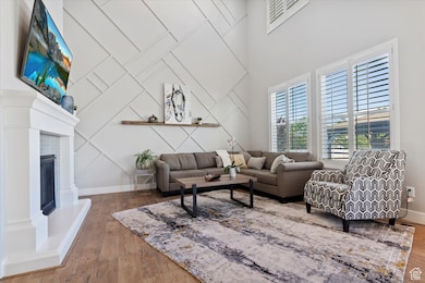 Living area with wood finished floors, a fireplace with raised hearth, and a decorative wall