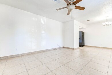 Open living and dining area with tile flooring, ceiling fan, and plenty of natural light — a versatile space ready for your personal touch.