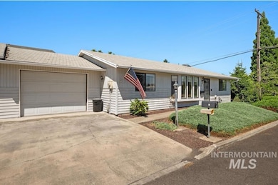 Single story home featuring concrete driveway, an attached garage, a shingled roof, and a front yard