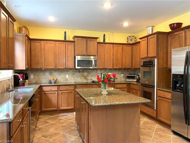 Plenty of cabinet space, double ovens, kitchen island, granite, tile floors, backsplash, recess lighting and bar area.
