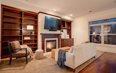 Living room with dark wood built-ins, a natural gas fireplace, and a large window that fills the space with natural light.