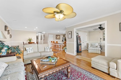 Living room featuring a ceiling fan, wood finished floors, ornamental molding, and recessed lighting