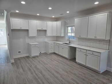 Kitchen featuring sink, white cabinets, light hard