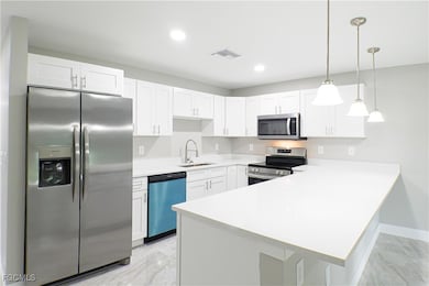 Kitchen featuring stainless steel appliances, a peninsula, pendant lighting, white cabinets, and recessed lighting