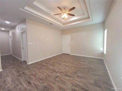 Spare room with a tray ceiling, ceiling fan, and dark wood-style floors