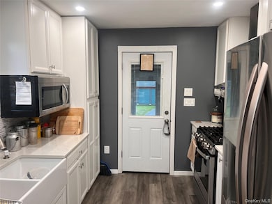 Kitchen featuring stainless steel appliances, white cabinetry, dark wood finished floors, recessed lighting, and backsplash