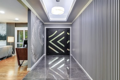 An impressive foyer showcasing refined design elements, including a custom wood wall that discreetly conceals the coat closet.