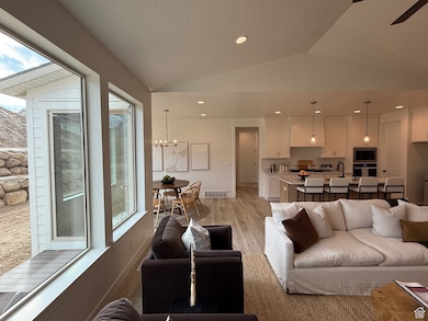 Living room featuring recessed lighting, visible vents, vaulted ceiling, a chandelier, and light wood-type flooring