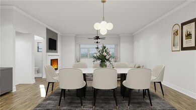 Dining area with wood finished floors, crown molding, a warm lit fireplace, and a chandelier