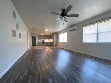 Unfurnished living room featuring dark wood-style floors, a ceiling fan, and a wall mounted air conditioner