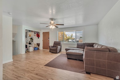 Living area with light wood-style floors, a ceiling fan, and a textured ceiling
