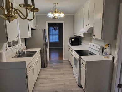 Kitchen with sink, white cabinetry, electric range
